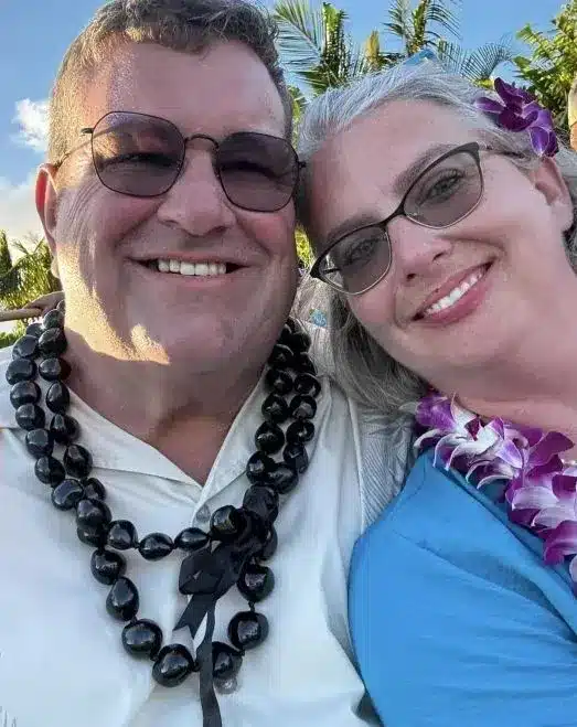 Jason and Stephanie Ramsey smiling together, wearing leis, in a tropical setting, representing the friendly and approachable team at Simply Maid.