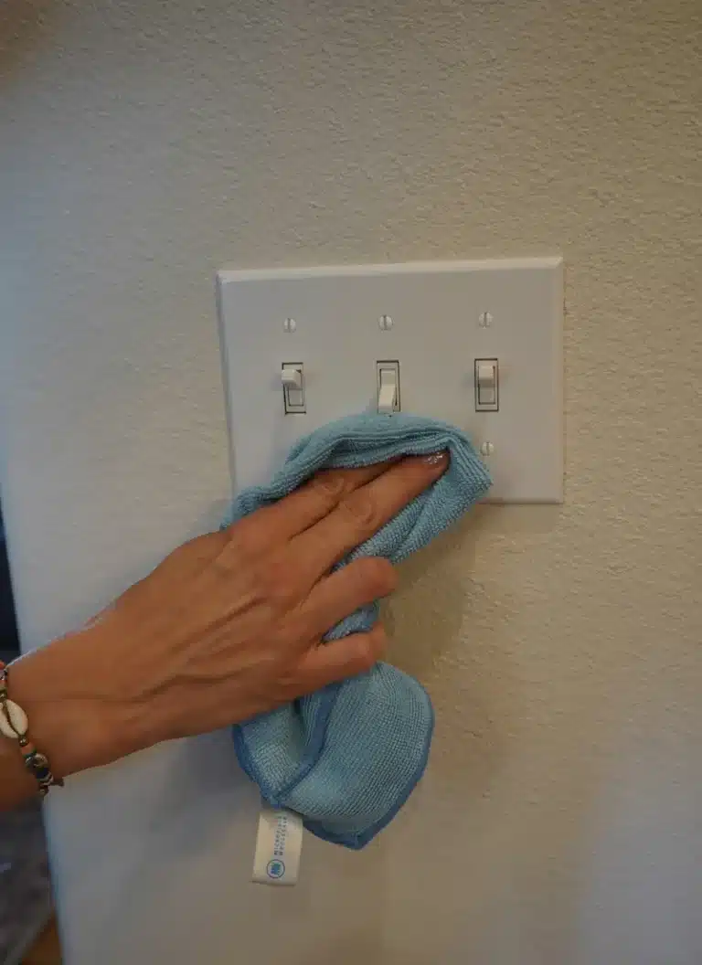 Simply Maid Sparkle Technician sanitizing light switches with a microfiber cloth