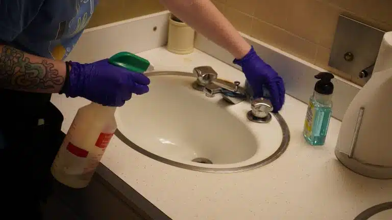 Simply Maid Sparkle Technician sanitizing a bathroom sink in gloves