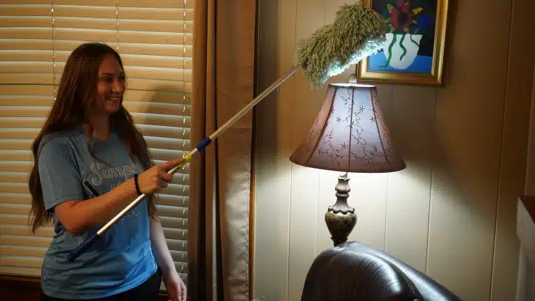 Simply Maid Sparkle Technician dusting a bedside lamp