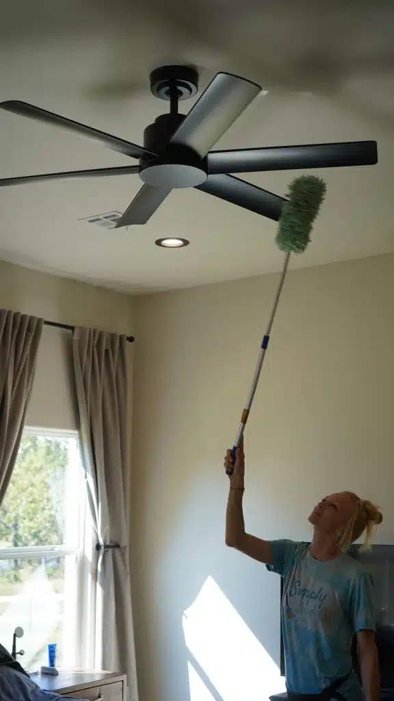 Simply Maid Sparkle Technician dusting a high ceiling fan with an extension duster
