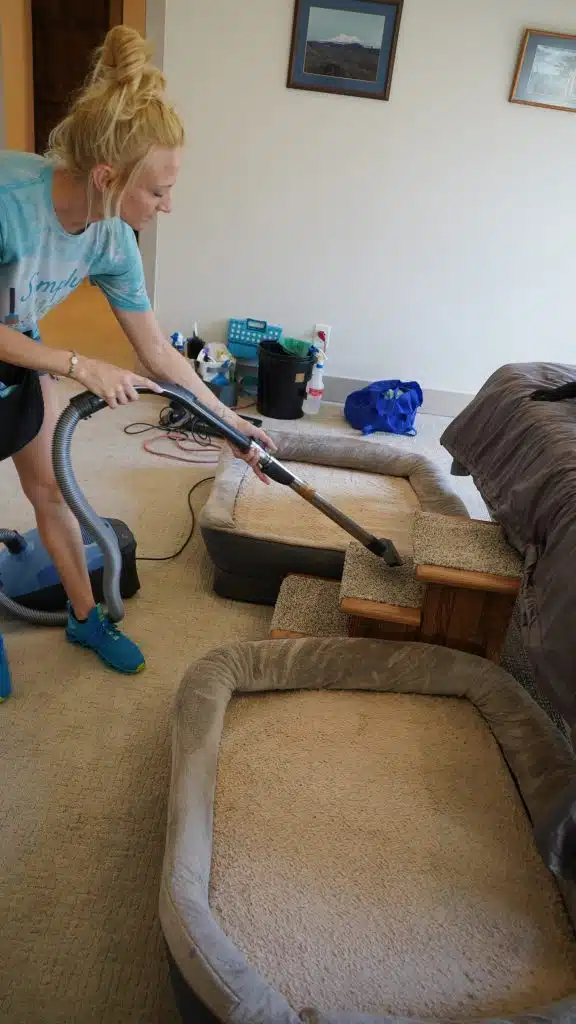 Simply Maid Sparkle Technician vacuuming a living room couch